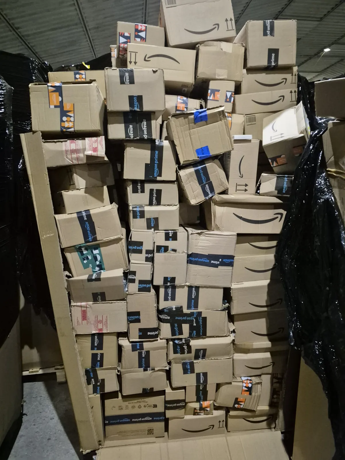 Wysoki stos oryginalnie zaklejonych kartonów Amazon Prime na palecie